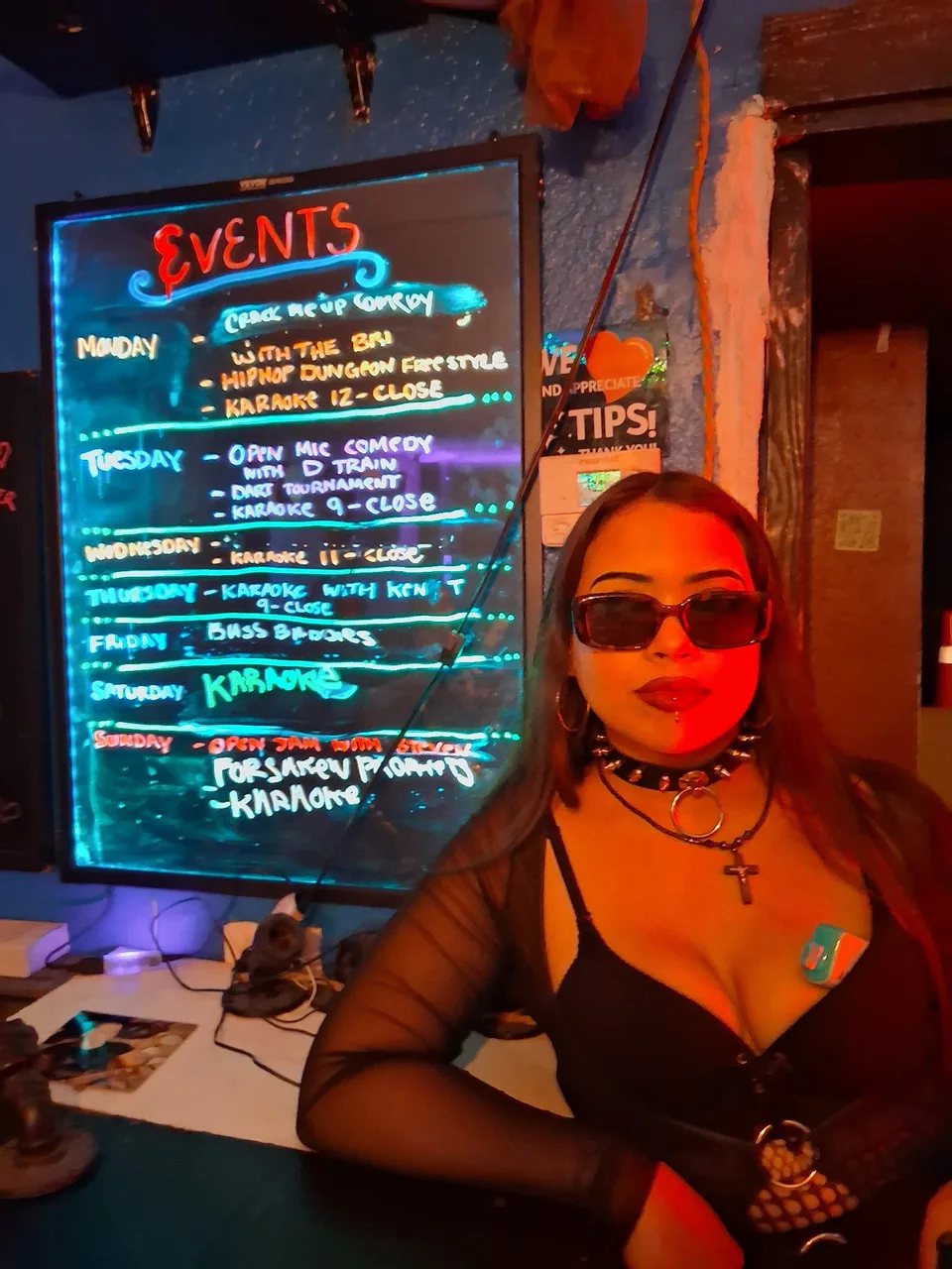 A woman pointing at the colorful weekly events board at Grumpys Underground