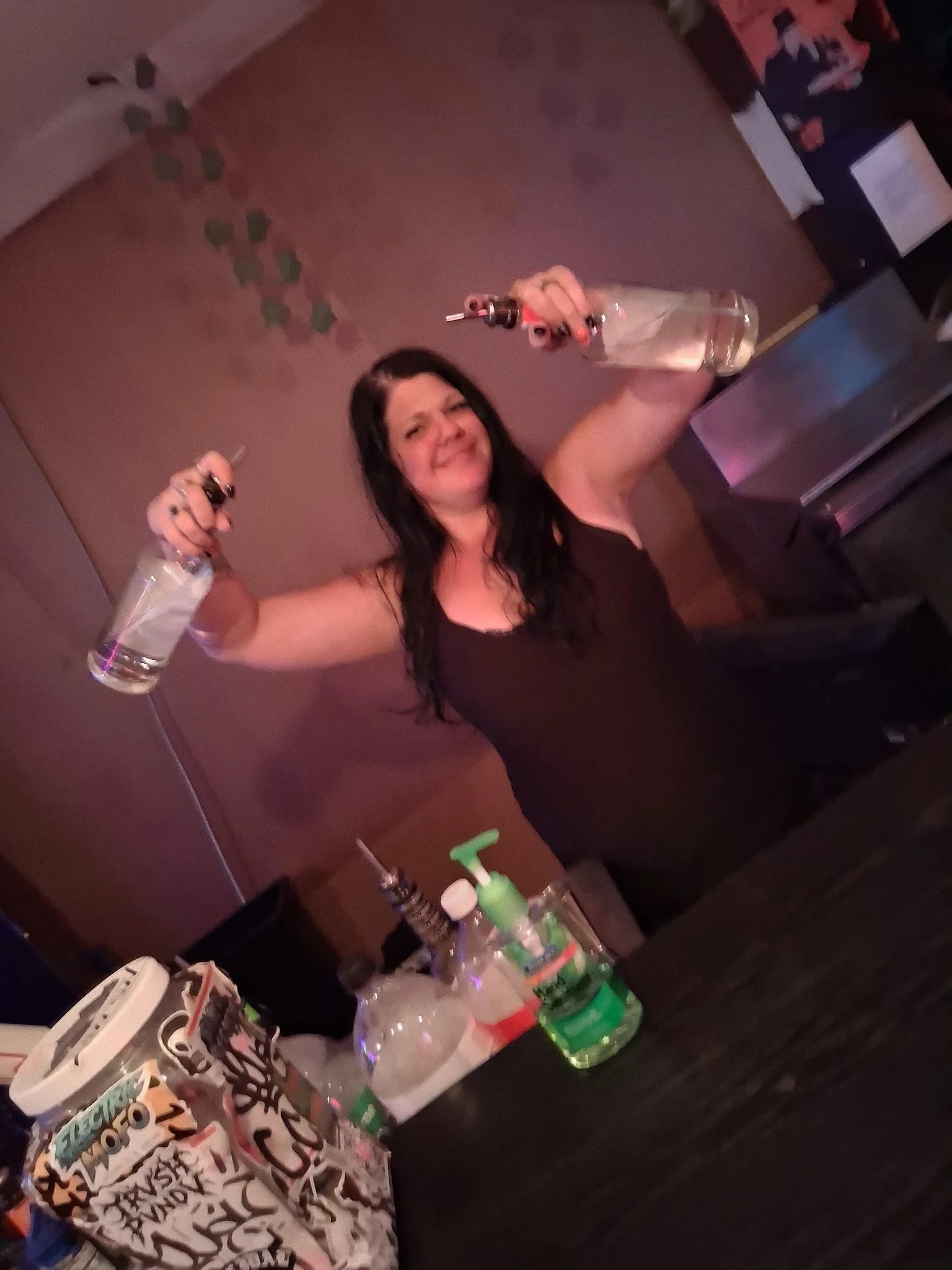 Allie smiling behind the bar while flair bartending with two bottles