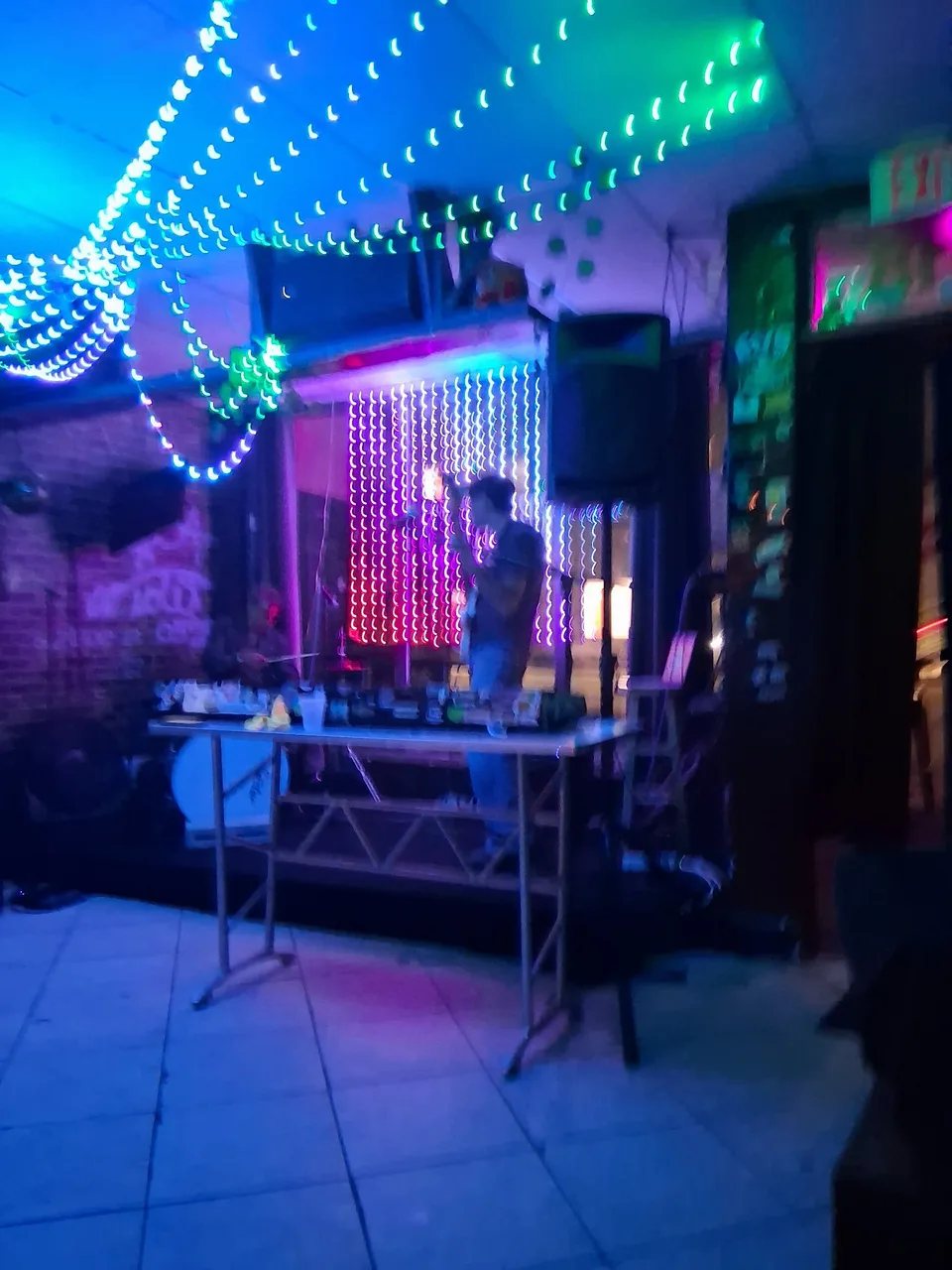 DJ setup under blue and green string lights inside Grumpys Underground