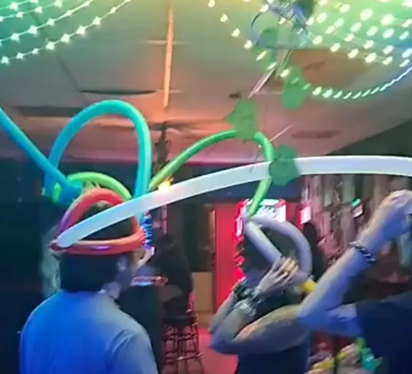 Friends wearing elaborate balloon hats under string lights